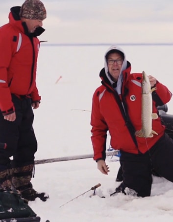 Un pêcheur sort un brochet appâté sous la glace.