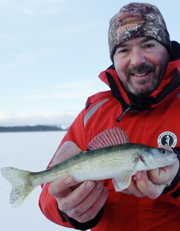 Un pêcheur montre un doré qu'il vient de pêcher sur la glace