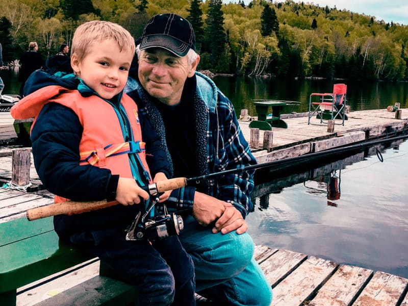 Un grand-père initie fièrement son petit-fils à la pêche lors de la Fête de la pêche.