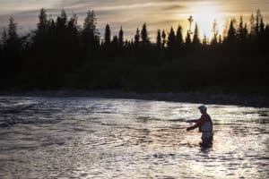 Un pêcheur à la mouche s'élance dans un lac , de l'eau jusqu'à mi-cuisse.