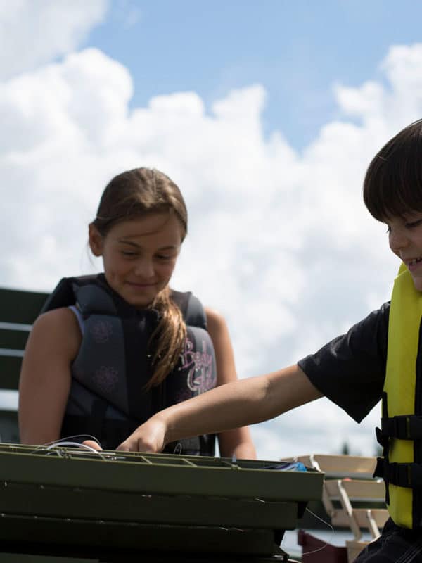 2 enfants fouillent dans leur coffre à pêche à la recherche du meilleur leurre.