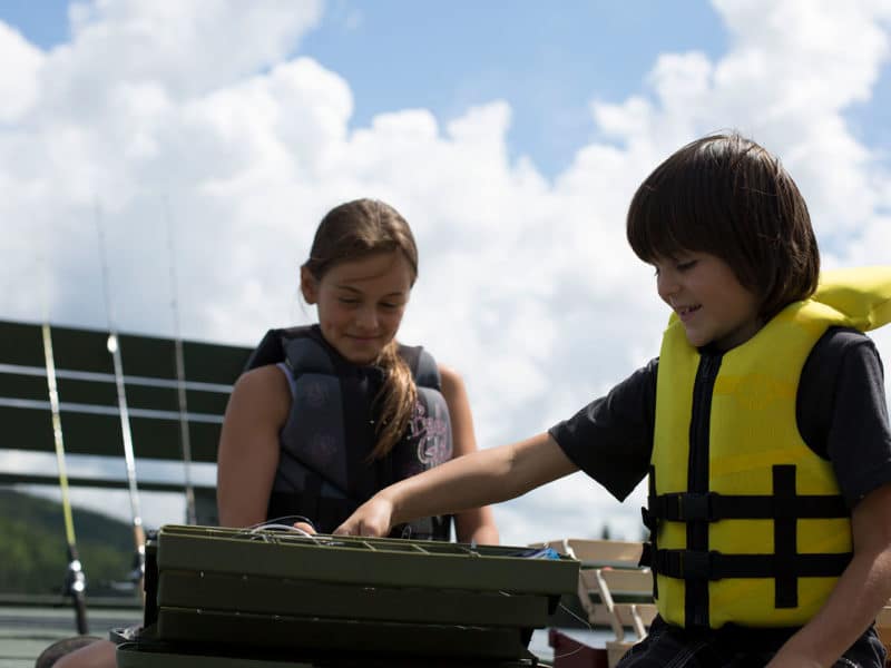 2 enfants fouillent dans leur coffre à pêche à la recherche du meilleur leurre.