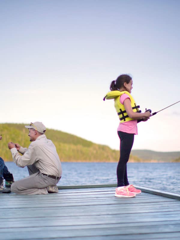 Un homme initie deux enfants à pêcher et à préparer leur équipement.