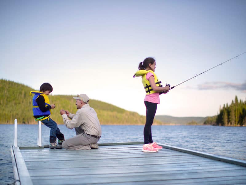 Un homme initie deux enfants à pêcher et à préparer leur équipement.