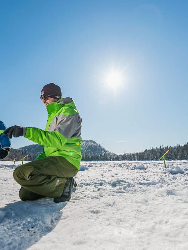 Un pêcheur montre à son fils à pêcher sur la glace à l'aide d'une brimbale.