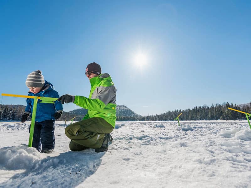 Un pêcheur montre à son fils à pêcher sur la glace à l'aide d'une brimbale.
