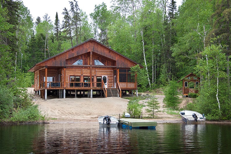 2 chaloupes sont attachées au quai d'un magnifique chalet en bois rond.