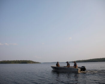 Trois pêcheurs en chaloupe s'éloignent au large à la recherche du meilleur spot de pêche.