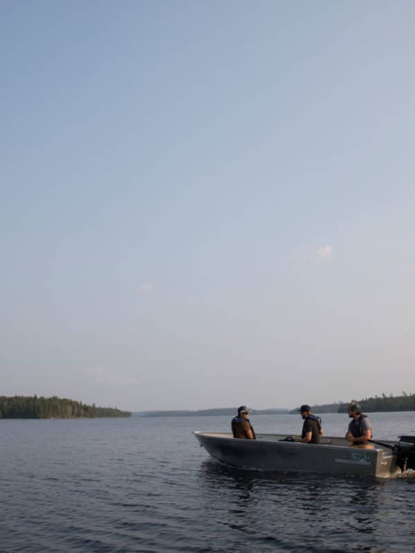 Trois pêcheurs en chaloupe s'éloignent au large à la recherche du meilleur spot de pêche.