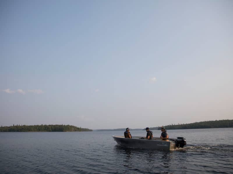 Trois pêcheurs en chaloupe s'éloignent au large à la recherche du meilleur spot de pêche.